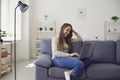 Online chat. Young woman works with a laptop using a web video camera while sitting on a sofa in a room. Royalty Free Stock Photo
