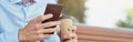 Online chatting. Side view of a happy businessman using smartphone and drinking coffee while relaxing on the bench Royalty Free Stock Photo