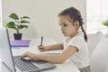 Online child education. Little girl makes video chat lesson laptop at home. Royalty Free Stock Photo