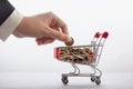 Online commerce and banking concept, businessman`s hand stacks coins in supermarket trolley, cashback background Royalty Free Stock Photo