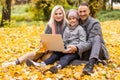 Online communication. Family using laptop and video calling , sitting on picnic blanket in garden.