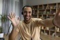 Online communication. Happy arab man in headphones making video call to friends or colleagues, waving hand at camera Royalty Free Stock Photo