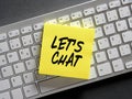 Online computer chatting concept. The word let's chat written on a sticky note paper on computer keyboard Royalty Free Stock Photo