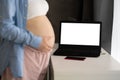 Online consultation. Pregnant woman talking with doctor via video call standing with laptop Royalty Free Stock Photo
