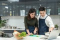 Online cooking class with computer. Asian Couple cooking together in home kitchen. Female slice vegetables and cooking with laptop Royalty Free Stock Photo