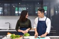 Online cooking class with computer. Asian Couple cooking together in home kitchen. Female slice vegetables and cooking with laptop Royalty Free Stock Photo