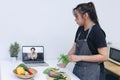 Online cooking classes. Woman watching and learn online cooking courses in the kitchen Royalty Free Stock Photo