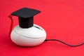 Online course, e-learning or internet study via website and online teaching concept, graduation hat on computer mouse on red Royalty Free Stock Photo