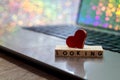 Online Dating concept with laptop and wood words LOOKING rainbow bokeh