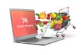 Online delivery of fruits and vegetables. Vegetables and fruits in the cart. Gray laptop.