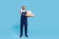 Online delivery order. Full length courier man in blue uniform holding cardboard boxes and mobile phone