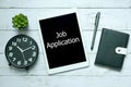 Online digital technology job application concept.Top view of clock,plant,notebook,pen and tablet written with Job Application on Royalty Free Stock Photo