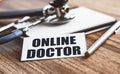 Online doctor - text inscription in a card on the wooden medical table. News information, consultation, appointment with a