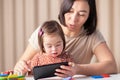 online education of children with down syndrome, a girl with a tablet and mom watch lessons