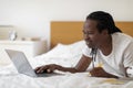 Online Education Concept. Black Young Man Using Laptop While Lying In Bed Royalty Free Stock Photo