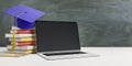 Online education concept with stack of books, blue graduate cap and empty black laptop screen on wooden table at blackboard