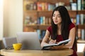 Online Education. Korean girl studying with laptop at cafe and taking notes