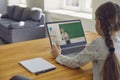 Online education.Little girl listens to the lesson online. On the laptop screen, an older woman teacher is at school Royalty Free Stock Photo