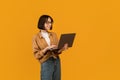 Online education programs. Excited young lady holding and using newest laptop over yellow background, free space Royalty Free Stock Photo