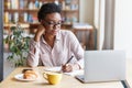 Online education. Serious black girl studying remotely on laptop from city cafe Royalty Free Stock Photo