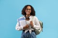 Online education. Smiling black female student with backpack and headphones holding notebooks and digital tablet Royalty Free Stock Photo
