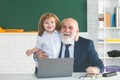 Online education. Teacher with pupil in classroom. Child with laptop. Kid is learning in class with senior mature Royalty Free Stock Photo