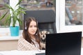 Online education. Webinar. A girl listens to a lecture on video communication at home, holds a dog in her arms