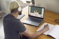 Online education. A young man sitting at a table at home using a laptop and a video call to listen to a lesson online. Royalty Free Stock Photo