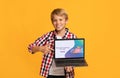 Smiling Caucasian boy pointing at laptop screen with Financial Literacy For Kids school website, orange background