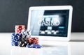 Online gambling on mobile casino concept. Stack of poker chips and tablet with slot machine on screen. Betting on internet. Royalty Free Stock Photo