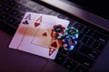 Online gambling theme. Aces with playing chips on a laptop's keyboard close-up Royalty Free Stock Photo