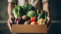 Online grocery shopping and home delivery: hands holding a box full of groceries. Eco friendly responsible lifestyle and shopping