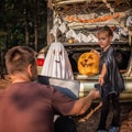 Online Halloween celebration. Kids getting mobile money on card at party in trunk of car