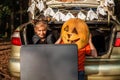 Online Halloween celebration. Kids scaring friends via internet at themed party in trunk of car