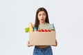Online home delivery, internet orders and grocery shopping concept. Confused woman holding box with her order, received