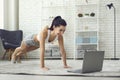 Online home sports. Young fit woman exercising to video tutorial indoors, doing plank or push up exercise