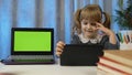 Child girl pupil doing homework with teacher using digital tablet at home, laptop green screen Royalty Free Stock Photo