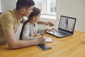 Online learning lessons education school. Father and daughter are doing online education with a teacher using a laptop Royalty Free Stock Photo