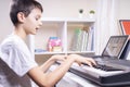 Online learning, remote education. Boy watching video at tablet computer, playing digital piano and singing at home Royalty Free Stock Photo