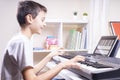 Boy watching video lesson at tablet computer and having fun playing piano at home. Online learning remote education Royalty Free Stock Photo