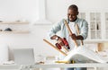 Online lesson for assembling furniture with own hands. African american man collecting chair and looking at laptop Royalty Free Stock Photo