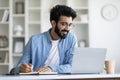 Online Lesson. Smiling Young Indian Man Using Laptop And Taking Notes Royalty Free Stock Photo