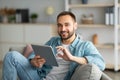 Online life concept. Happy young man using tablet computer, working or studying from home Royalty Free Stock Photo