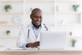 Online medical consultation. Highly qualified black doctor consultating patients distantly using laptop computer