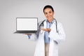 Online medical health support. Cheerful latin female doctor with stethoscope showing blank screen on laptop, mockup Royalty Free Stock Photo
