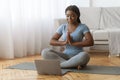 Online Meditation. Black Lady Practicing Yoga In Front Of Laptop At Home