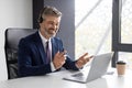 Online Meeting. Smiling mature businessman in headset making video conference via laptop Royalty Free Stock Photo