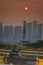 An online motorcycle taxi driver stops for a moment on the side of the road with a view of the yellowing sunset