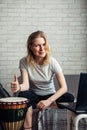 Online music lessons during quarantine due to coronavirus pandemic. Remote teaching to play the drum. Young woman watches video