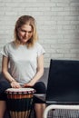 Online music lessons during quarantine due to coronavirus pandemic. Remote teaching to play the drum. Young woman watches video